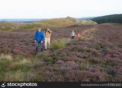 Couples Hiking Across Moorland Covered With Heather
