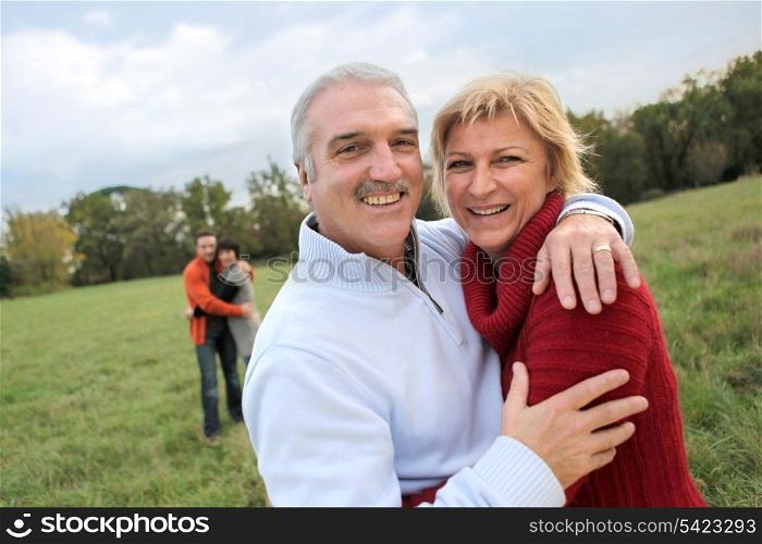 Couples hugging in a field