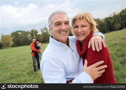Couples hugging in a field