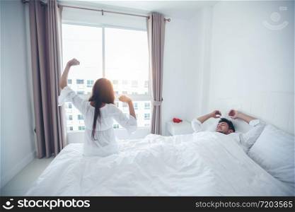 couples lover waking up in her bed fully rested and open the curtains in the morning to get fresh air.