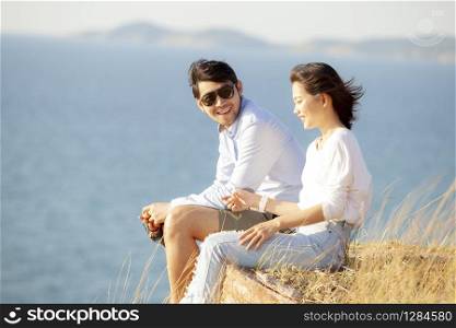 couples of younger asian man and woman relaxing with happiness on vacation beach