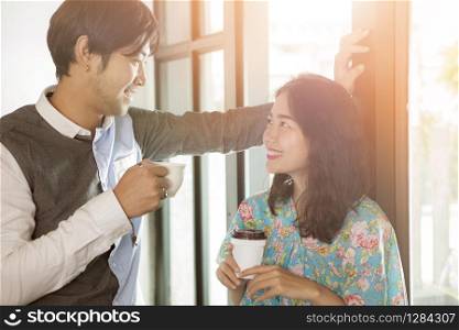 couples of younger asian man and woman with coffee cup in hand toothy smiling face happiness and relaxing discussing