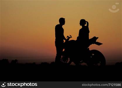 Couples with a motorcycle for traveling at the sunset.