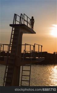 Courage and Jump: Silhouette of Child Before Jumping from High Board into Water, Fun in the Summer