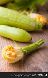 Courgettes with flowers on the wooden background