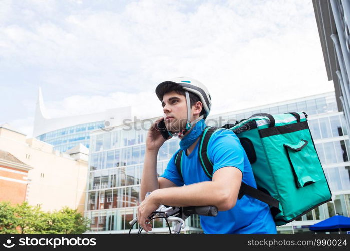 Courier On Bicycle Delivering Food In City Using Mobile Phone