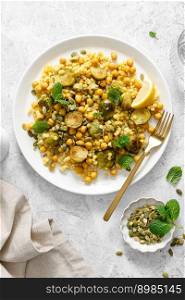 Couscous brussels sprouts and chickpeas warm salad with pumpkin seeds. Healthy vegetarian diet food. Top view 