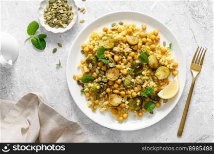 Couscous brussels sprouts and chickpeas warm salad with pumpkin seeds. Healthy vegetarian diet food. Top view 