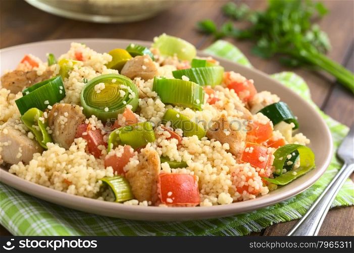 Couscous dish with chicken, leek and tomato served on plate, photographed with natural light (Selective Focus, Focus in the middle of the dish)