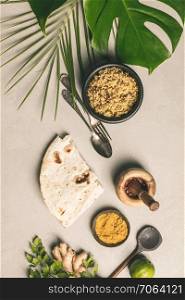 Couscous, green leaf and cooking ingredients on concrete background. Flat lay. Healthy vegetarian food and cooking concept
