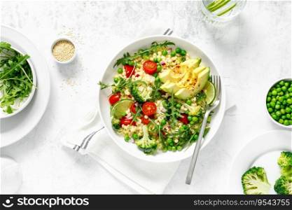 Couscous salad with broccoli, green peas, tomatoes, avocado and fresh arugula. Healthy natural plant based vegetarian food for lunch, israeli cuisine, top view