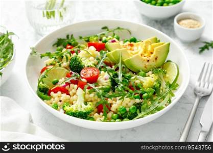 Couscous salad with broccoli, green peas, tomatoes, avocado and fresh arugula. Healthy natural plant based vegetarian food for lunch, israeli cuisine