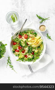 Couscous salad with broccoli, green peas, tomatoes, avocado and fresh arugula. Healthy natural plant based vegetarian food for lunch, israeli cuisine, top view