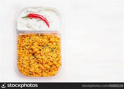Couscous salad with yogurt dip in lunch box on white wooden background , top view