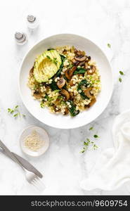 Couscous with avocado, spinach and sauteed champignon mushrooms with onion, top down view