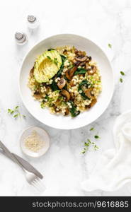 Couscous with avocado, spinach and sauteed champignon mushrooms with onion, top down view