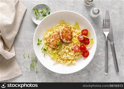 Couscous with chicken patties, cutlets and tomatoes, top down view