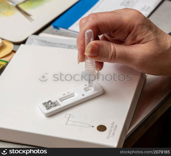 Covid-19 antigen tests underway with the buffer solution being dripped into the test area of the results strip. Self-test kit for Covid-19 with buffer solution being dripped onto test strip