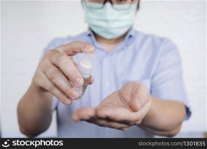 COVID-19, Close up man using bottle of antibacterial wash hand sanitizer gel dispenser, against Novel coronavirus (2019-nCoV) at home. Home isolation and Healthcare concept.