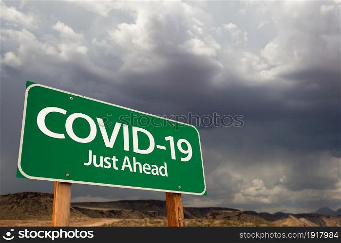 COVID-19 Coronavirus Green Road Sign Against Ominous Stormy Cloudy Sky.