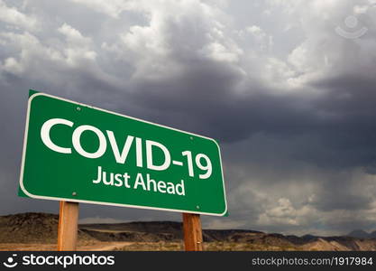 COVID-19 Coronavirus Green Road Sign Against Ominous Stormy Cloudy Sky.