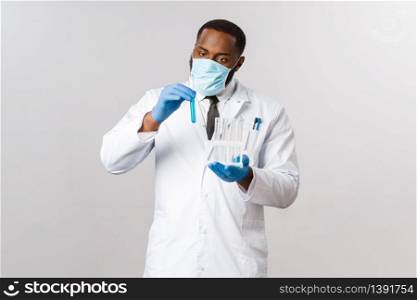 Covid-19, coronavirus patient treatment and laboratory concept. Focused and careful african-american doctor in latex gloves and medical face mask, look serious at test-tube, invent cure, vaccine.. Covid-19, coronavirus patient treatment and laboratory concept. Focused and careful african-american doctor in latex gloves and medical face mask, look serious at test-tube, invent cure, vaccine