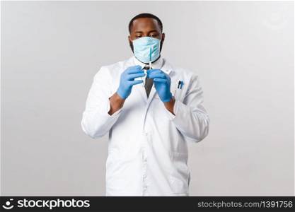 Covid-19, coronavirus patient treatment and laboratory concept. Portrait of handsome professional african-american doctor in medical face mask and latex gloves, hold syringe with vaccine.. Covid-19, coronavirus patient treatment and laboratory concept. Portrait of handsome professional african-american doctor in medical face mask and latex gloves, hold syringe with vaccine