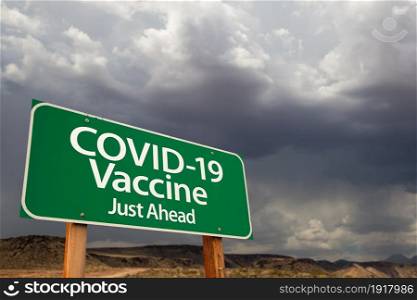 COVID-19 Coronavirus Vaccine Green Road Sign Against Ominous Stormy Cloudy Sky.
