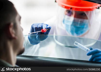 COVID-19 drive-thru patient specimen collection,female medical worker performing nasal swab on young man through vehicle window,Coronavirus point of care rt-PCR diagnostic at testing site location