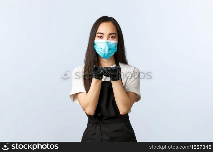 Covid-19, social distancing, small coffee shop business and preventing virus concept. Cute young asian waitress, barista in medical mask and gloves hold hands near lips as if blowing kiss.. Covid-19, social distancing, small coffee shop business and preventing virus concept. Cute young asian waitress, barista in medical mask and gloves hold hands near lips as if blowing kiss