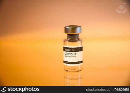 Covid-19 vaccine bottle on a yellow laboratory background. Covid-19 vaccine bottle on a yellow background
