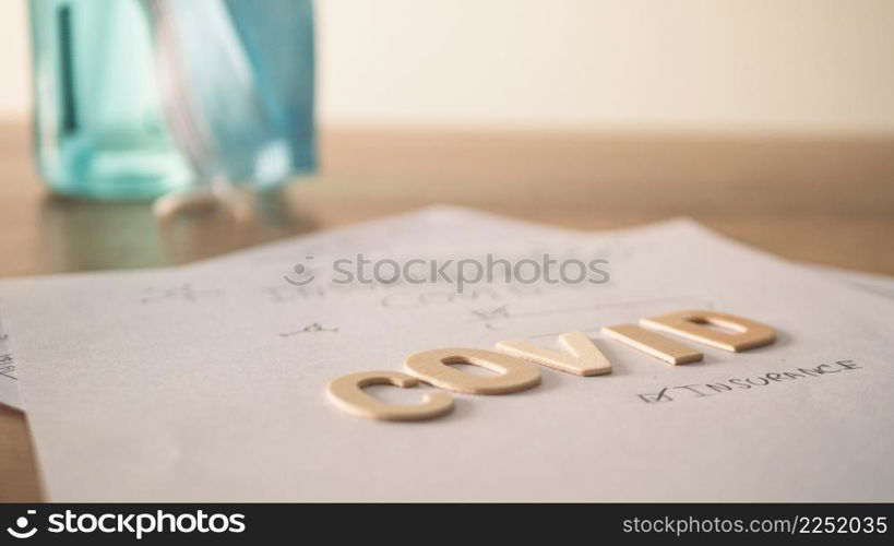 Covid insurance form with blurred alcohol bottle. Papers on the table.