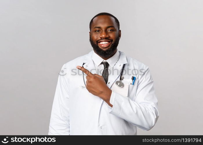 Covid19, hospital check-up and healthcare concept. Handsome enthusiastic african-american bearded doctor explain how to follow prescribtion at hospital, invite patient to clinic, point left.. Covid19, hospital check-up and healthcare concept. Handsome enthusiastic african-american bearded doctor explain how to follow prescribtion at hospital, invite patient to clinic, point left