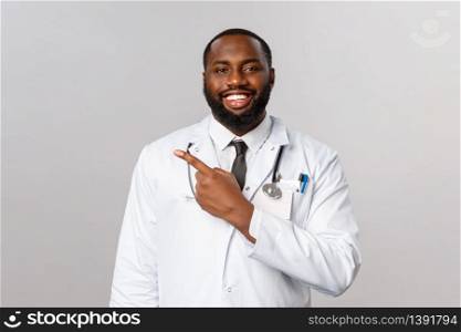 Covid19, hospital check-up and healthcare concept. Handsome enthusiastic african-american bearded doctor explain how to follow prescribtion at hospital, invite patient to clinic, point left.. Covid19, hospital check-up and healthcare concept. Handsome enthusiastic african-american bearded doctor explain how to follow prescribtion at hospital, invite patient to clinic, point left
