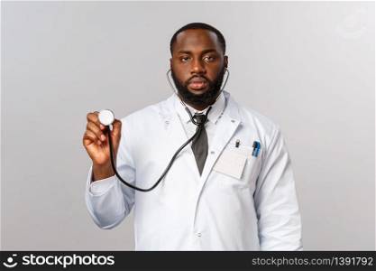 Covid19, hospital check-up and healthcare concept. Serious-looking african-american male doctor in white coat, physician checking patient lungs as listening breathing with stethoscope.. Covid19, hospital check-up and healthcare concept. Serious-looking african-american male doctor in white coat, physician checking patient lungs as listening breathing with stethoscope