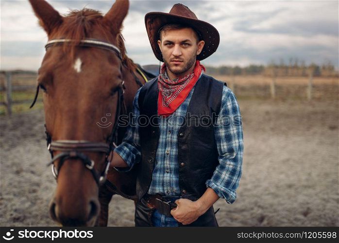 Cowboy in jeans and leather jacket poses with horse on texas farm, western. Vintage male person with animal, american culture. Cowboy poses with horse on texas farm