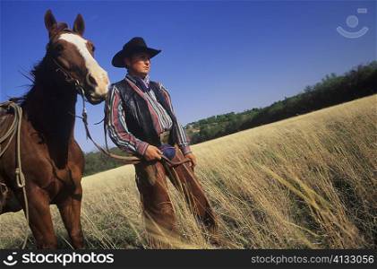Cowboy standing with a horse on a field, Texas, USA