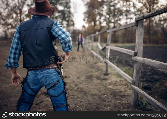 Cowboy with gun prepares to gunfight, back view, lucky strike on texas ranch, western. Vintage male person with revolver, wild west tradition