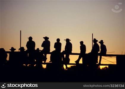 Cowboys Sitting on Fence in the Sunset