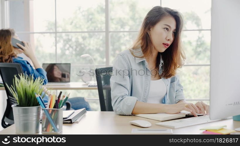 Coworkers looking at a computer and discussing over new business plan. Business team working together on computer in office. Professional business women working at her office.