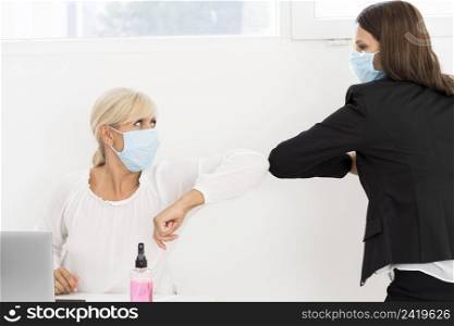 coworkers wearing masks elbow bump each other