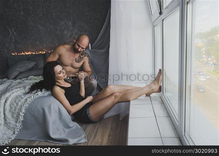 Cozy atmosphere in the conversation of a young couple.. Gently hugging the young couple sitting near the window 103.