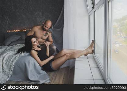 Cozy atmosphere in the conversation of a young couple.. Gently hugging the young couple sitting near the window 103.