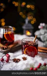Cozy atmosphere with glass of Mulled wine, Christmas winter alcohol drink decorated by snow and christmas lights. glass of Mulled wine
