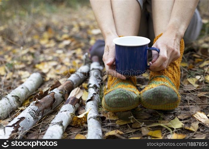 cozy autumn - girl resting in nature. feet in socks and a cup in hands close-up