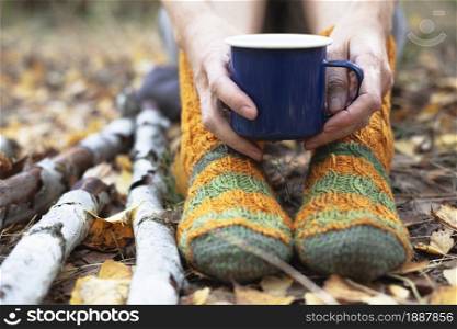 cozy autumn - girl resting in nature. feet in socks and a cup in hands close-up