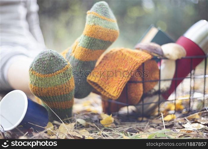 cozy autumn - girl resting in nature. woolen socks, a thermos with a cup, a book and mushrooms in the basket