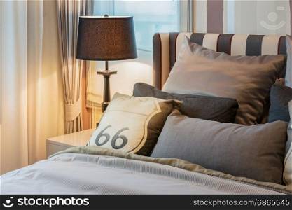 cozy bedroom interior with dark brown pillows and reading lamp on bedside table