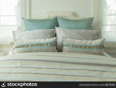 cozy bedroom interior with green pillows and reading lamp on bedside table