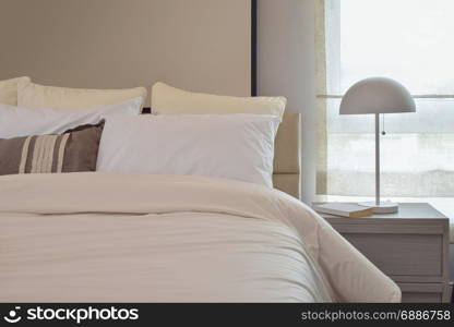 Cozy bedroom interior with pillows and reading lamp on bedside table